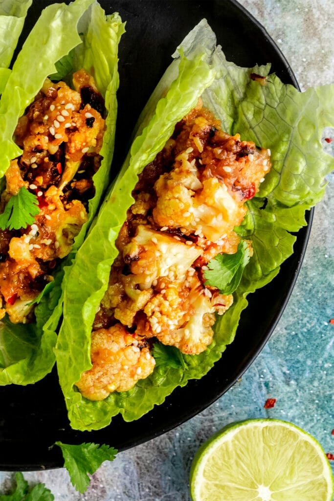 close up of sticky sesame cauliflower in a lettuce wrap topped with sesame seeds