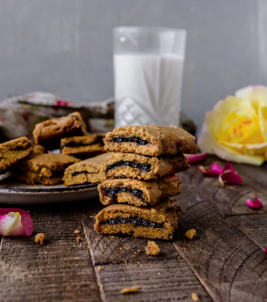stack of fig newton cookies on a wooden table next to a glass of milk