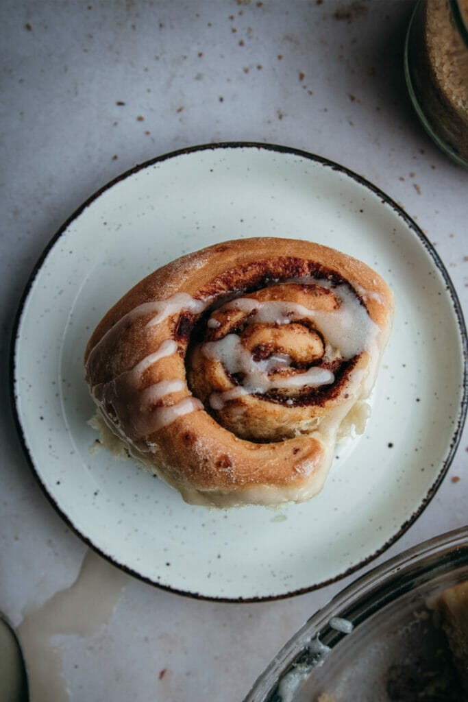 overhead shot of one cinnamon roll on a white plate
