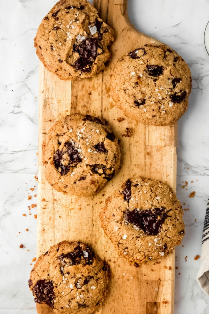 tray of four tahini chocolate chip cookies on a wooden board