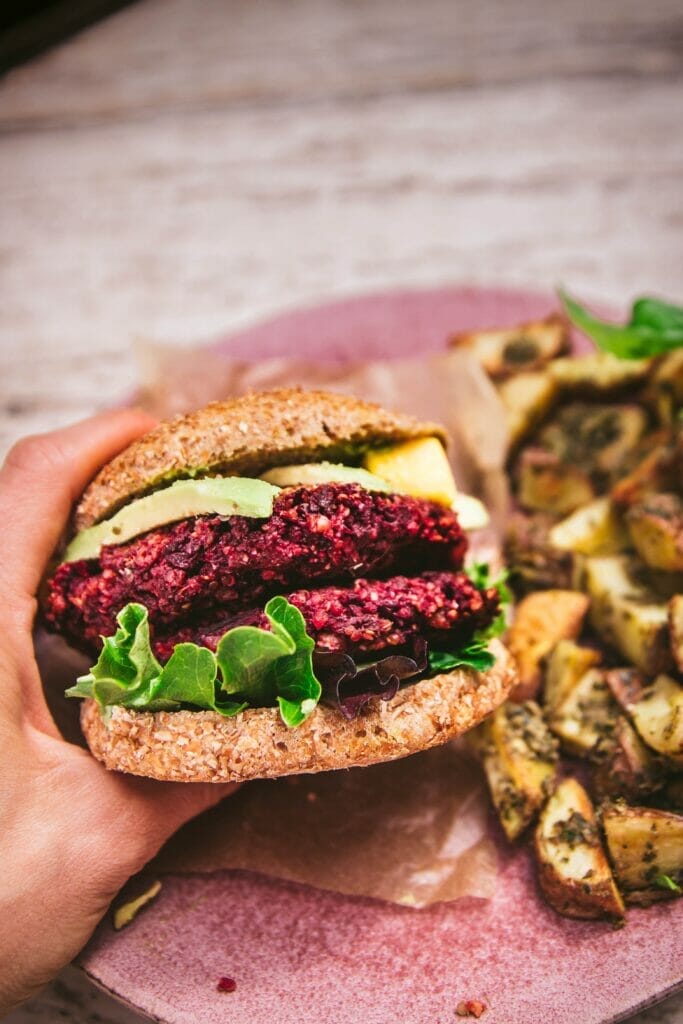 hand holding a vegan quinoa beet burger