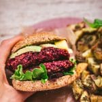 hand holding a vegan quinoa beet burger