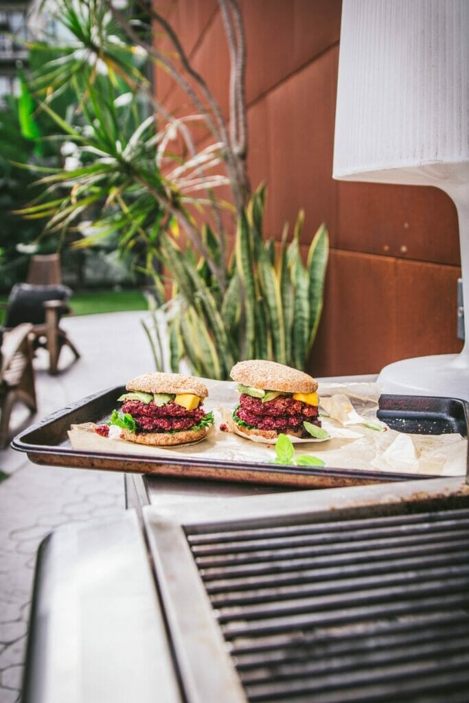 two quinoa beet burgers next to a grill
