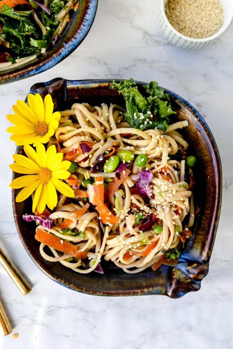 overhead shot of bowl of 15 minute sesame ginger noodles on a marble table with flowers