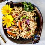 overhead shot of bowl of 15 minute sesame ginger noodles on a marble table with flowers