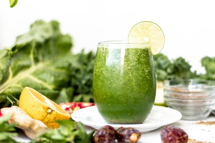 large glass with green smoothie and lime
