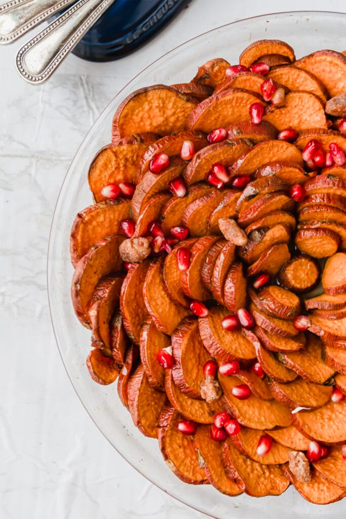 cinnamon roasted sweet potatoes in a pie dish with pomegranate