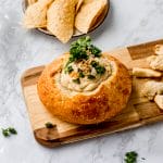 bread bowl with onion dip on a wooden tray