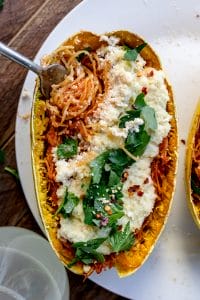 fork twirling strands of spaghetti squash in a boat with cheese