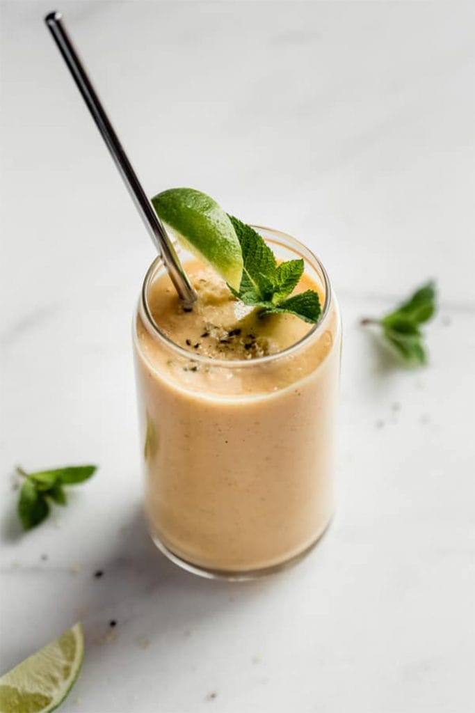 papaya smoothie in glass with lime and straw