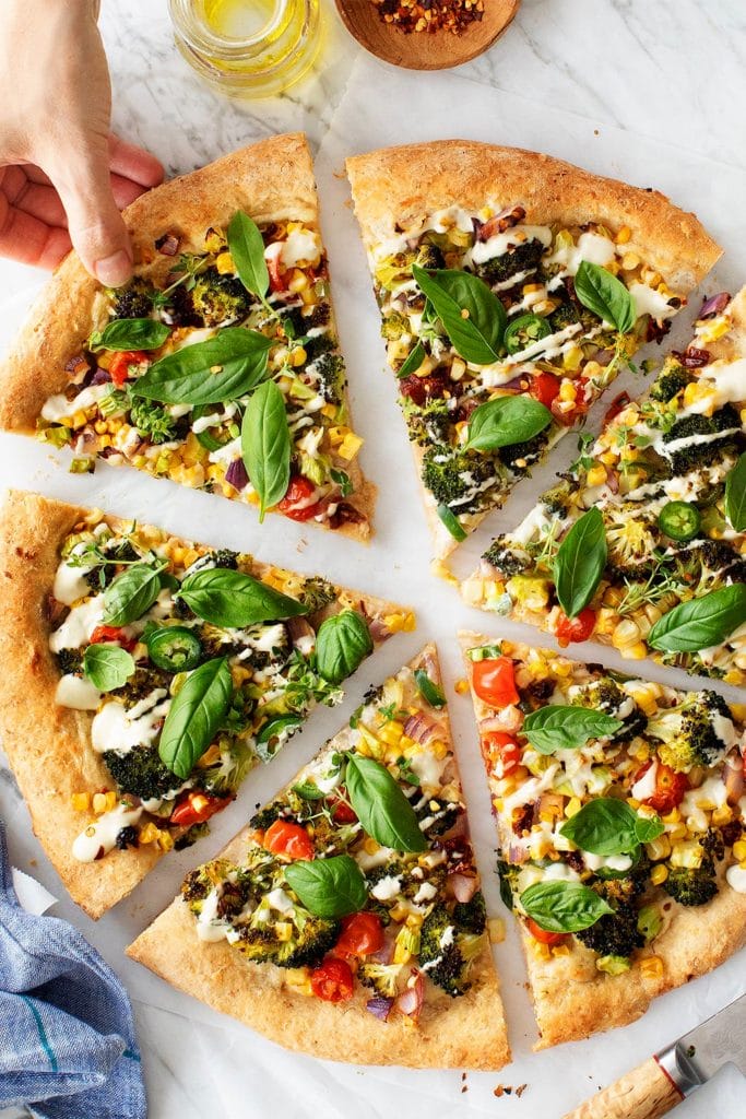 slices veggie pizza with hand reaching for one slice