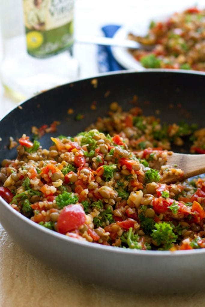 pan with lentil tomato salad and wooden spoon