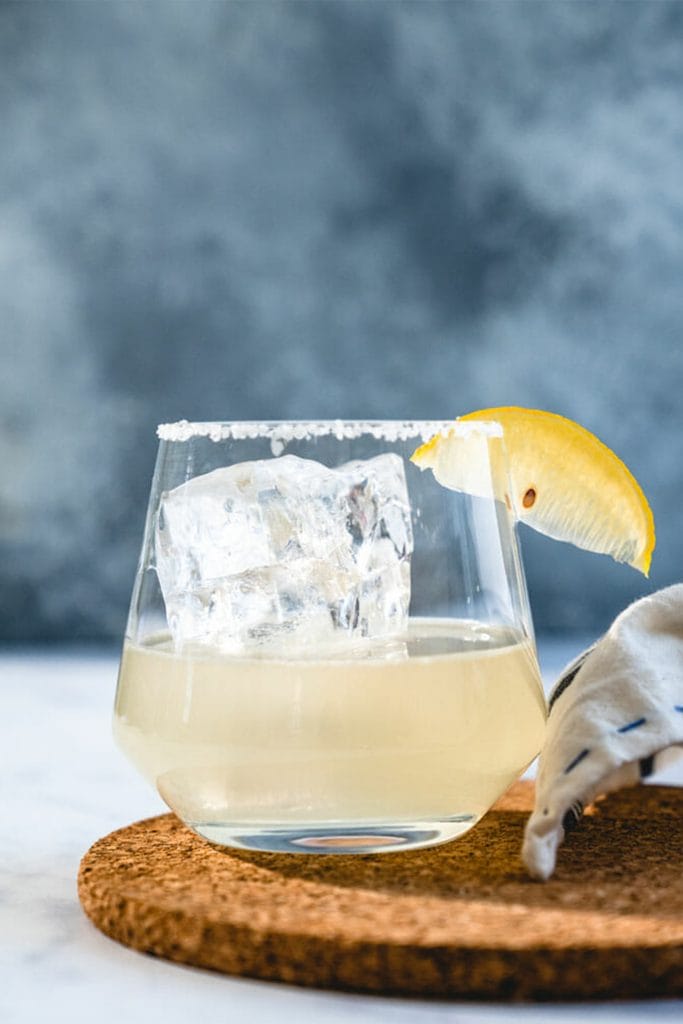glass with large ice cube and lemon wedge