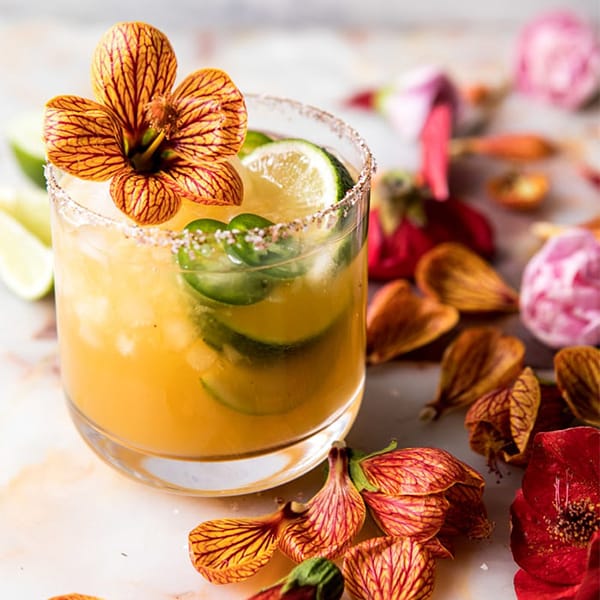 yellow margarita with ginger and mango and edible orange flowers