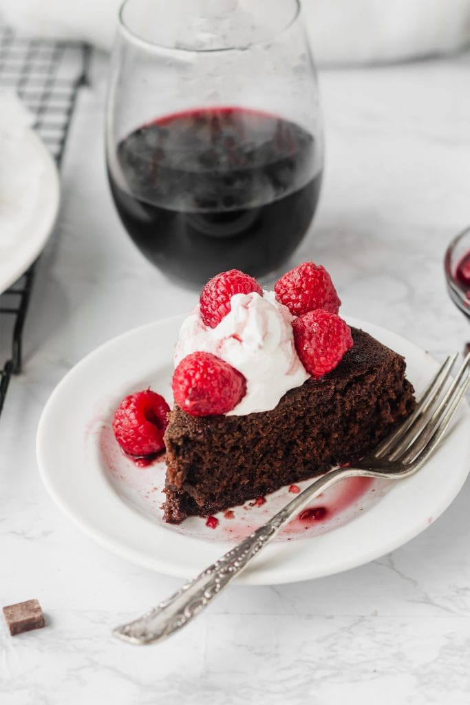 slice of vegan chocolate cake with glass of red wine in background