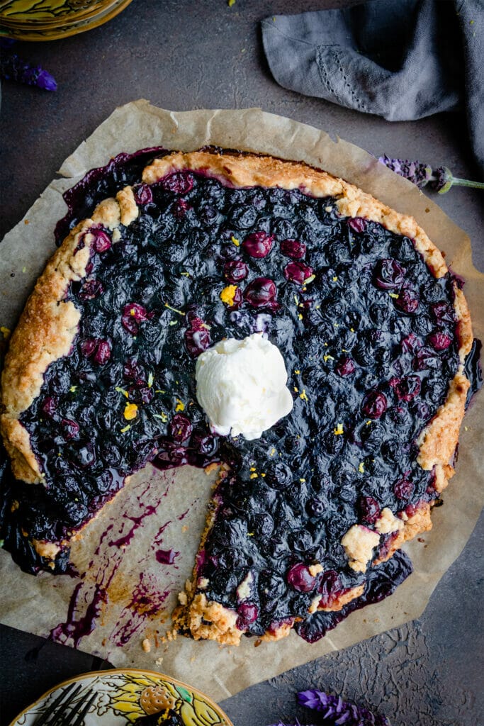 overhead shot of vegan berry galette with a scoop of ice cream in the center and one slice cut out of the bottom left side