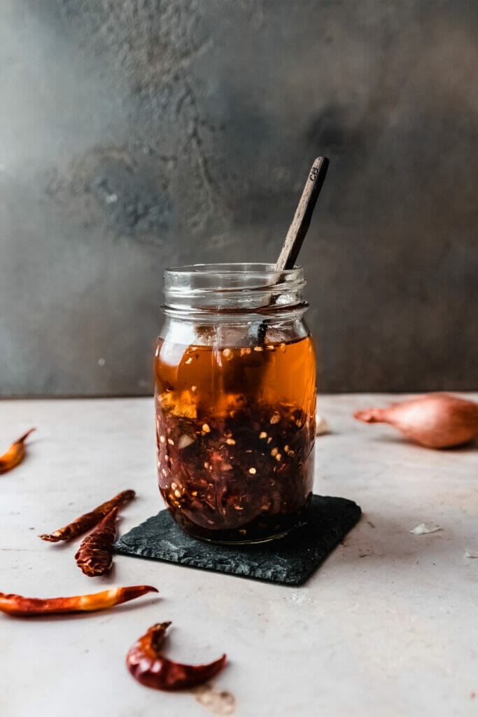 jar of homemade chili crisp with a wooden spoon sticking out 