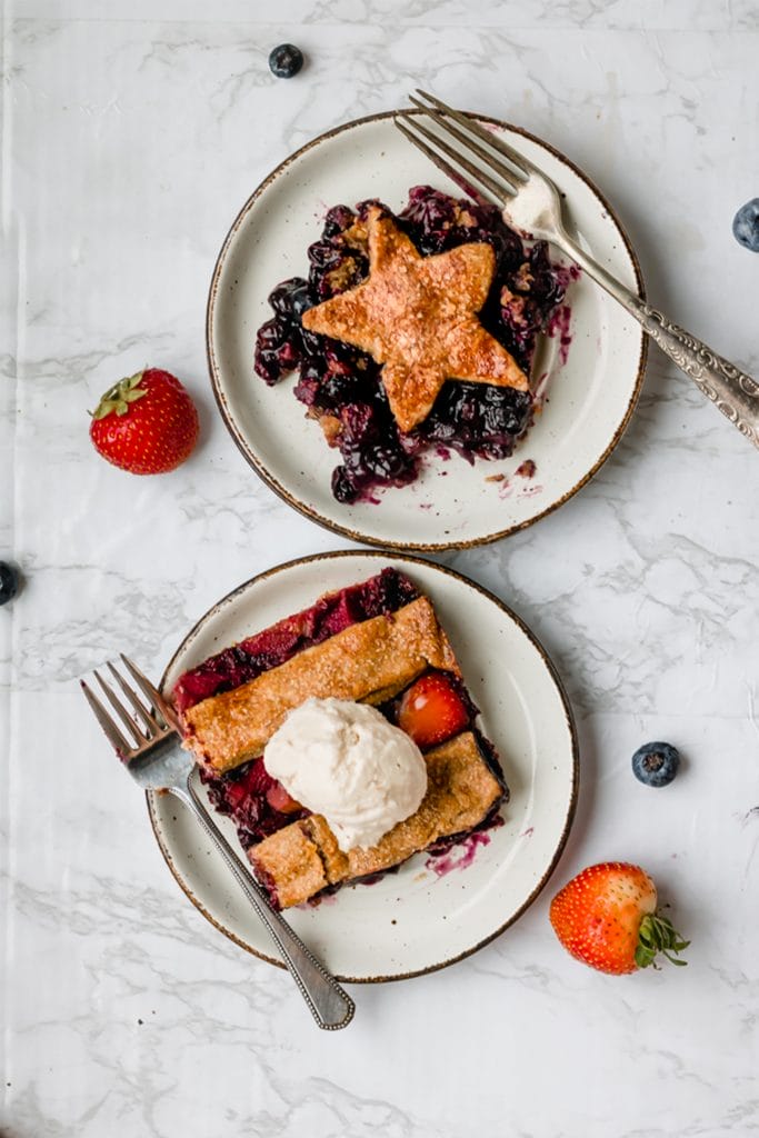 two slices of vegan pie on white plates with berries