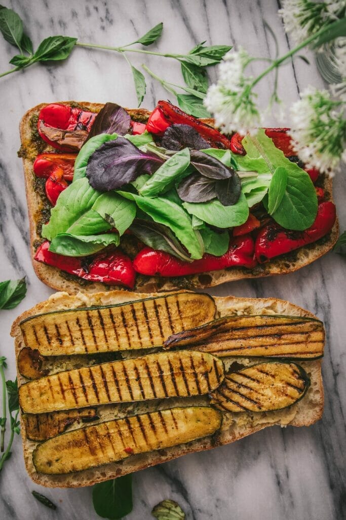 two slices of ciabatta bread topped with grilled vegetables on a tray