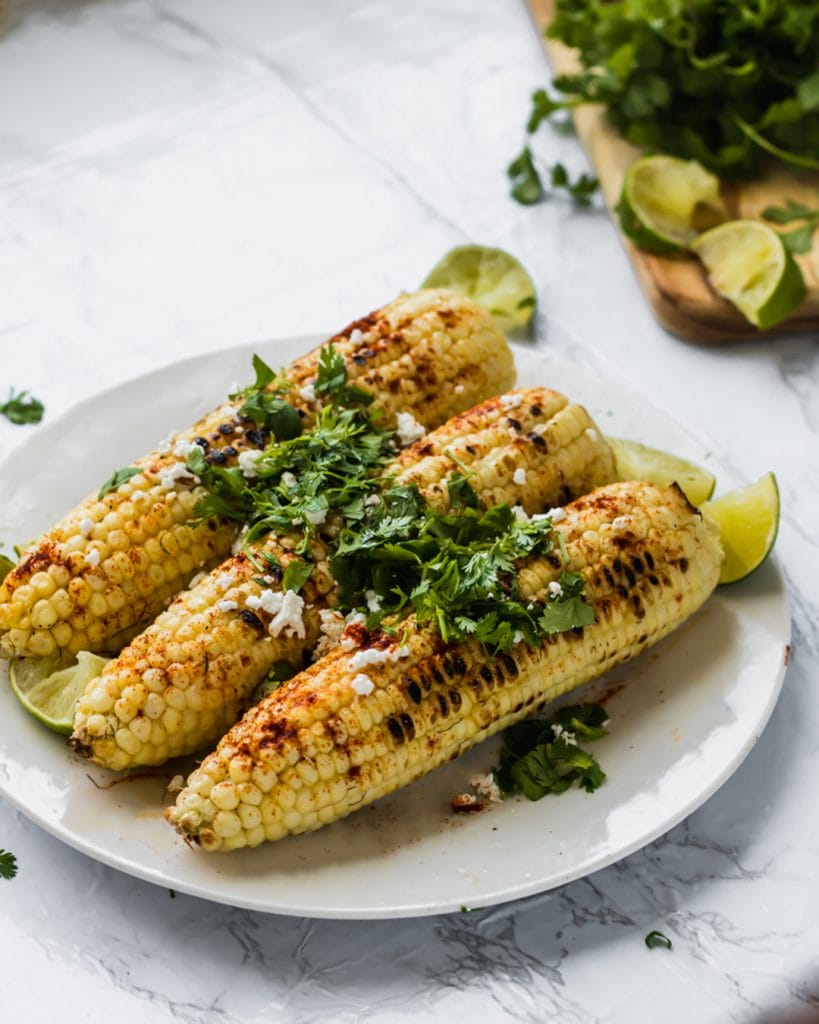 feta cheese on a three pieces of grilled corn