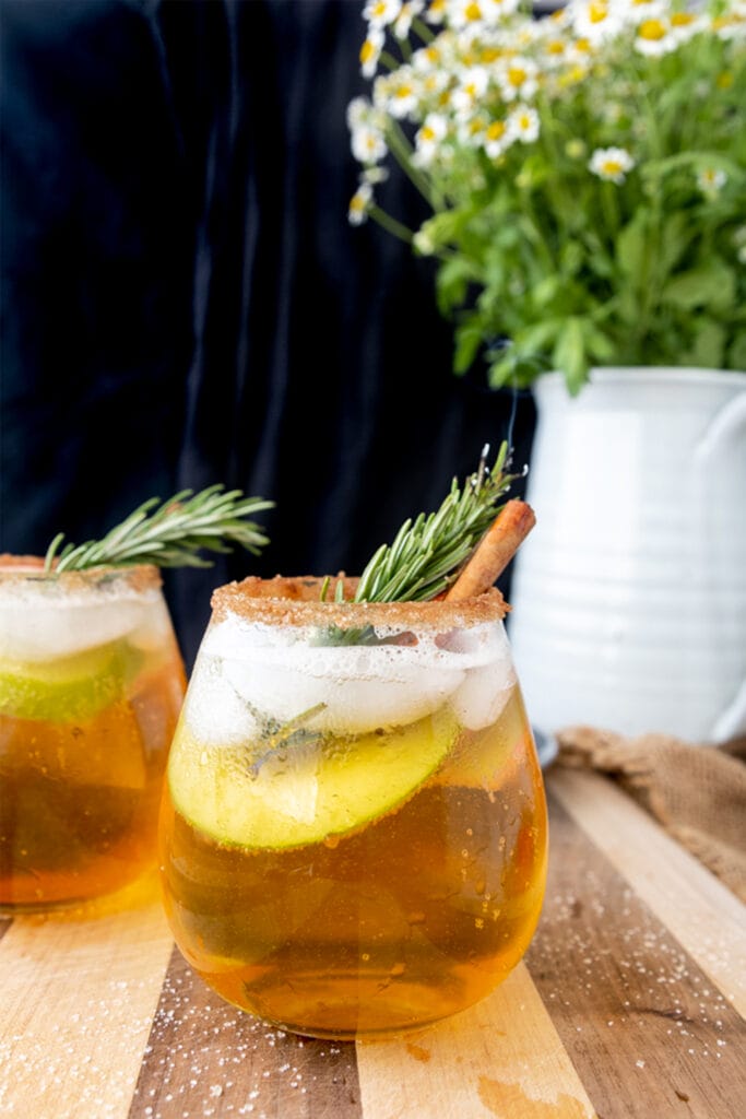 wine glass of apple cider sangria with a rosemary branch