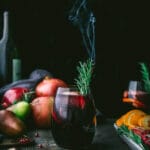 glass of autumn sangria with a burnt sprig of rosemary