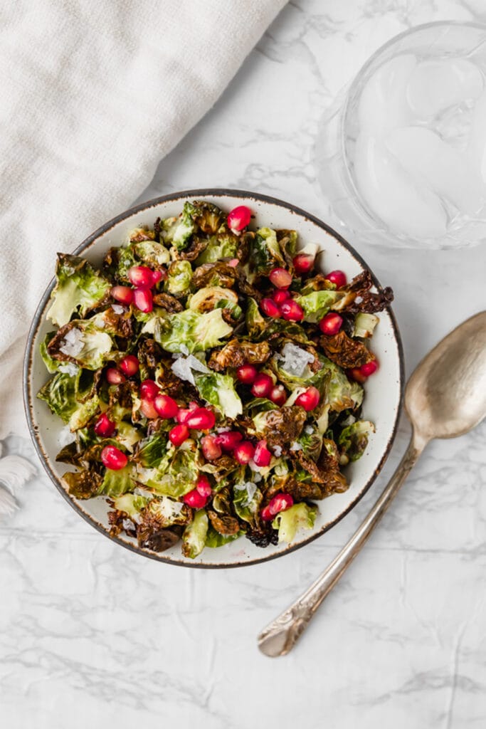 Crispy Brussels Sprout Chips, a fun salad option ready in just 15 minutes! Individual leaves of Brussels speckled with flaky sea salt and juicy pomegranate, making for a perfectly unique roasted Brussels sprouts side. This simple Thanksgiving recipe is delicious all year long!
