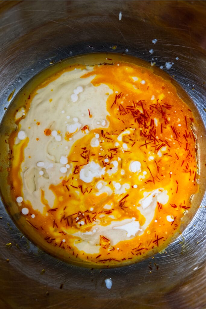 swirls of orange and red saffron in a milk mixture