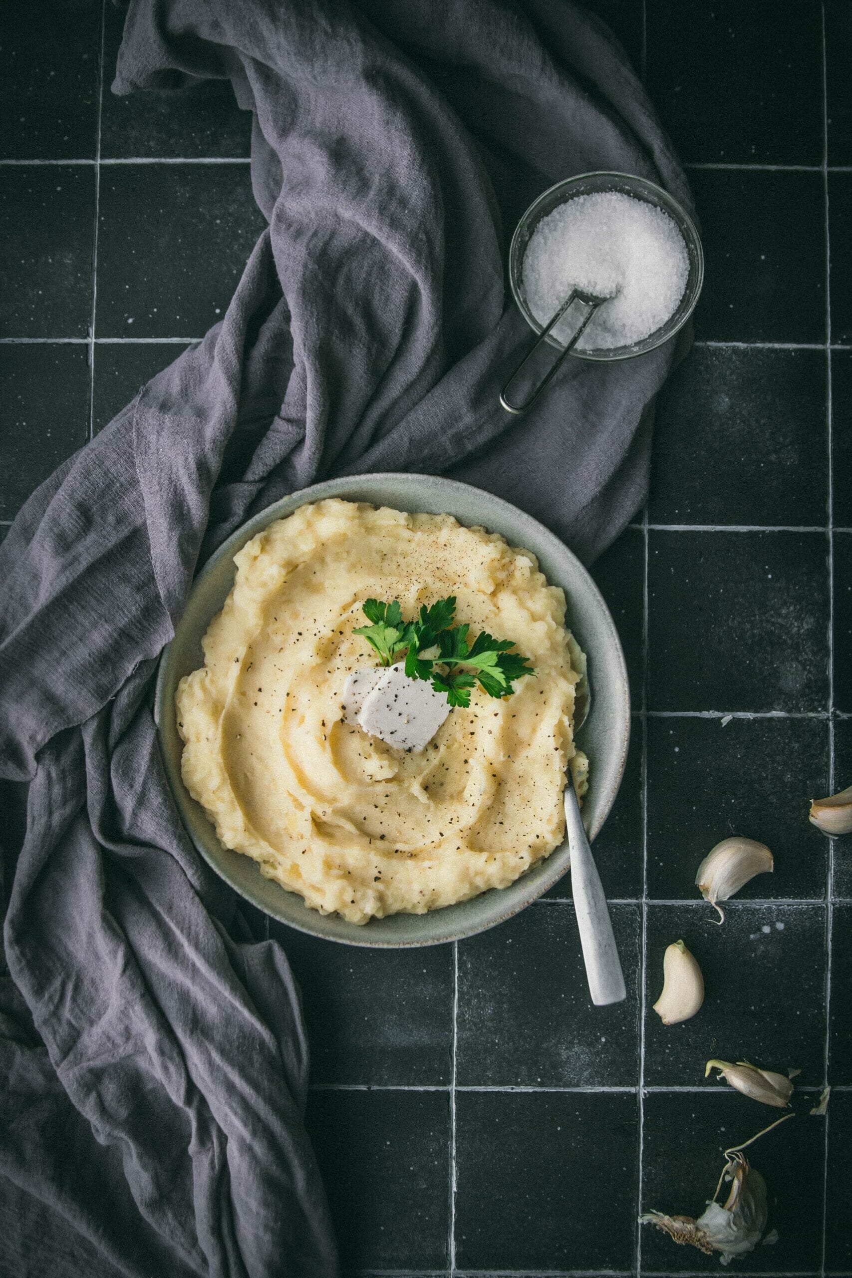bowl of vegan mashed potatoes with a grey cloth on a black tile table