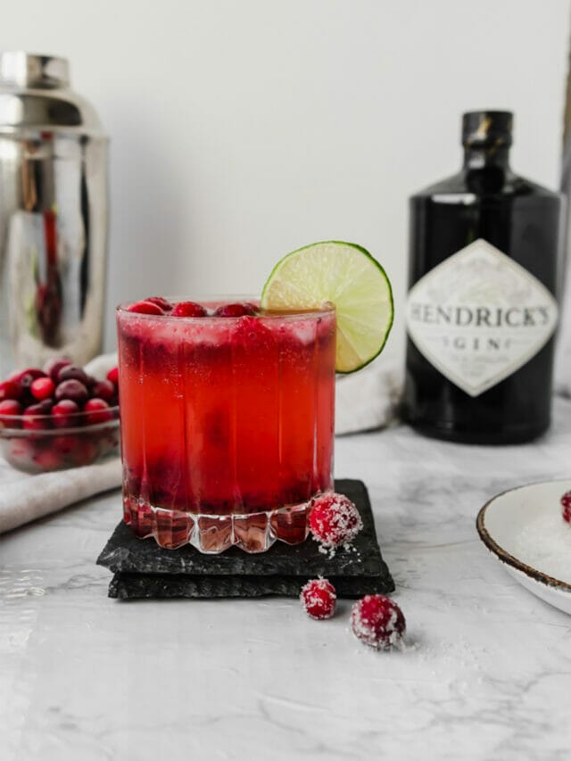 glass of cranberry gin fizz on a marble board in front of Hendricks gin
