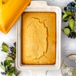 overhead shot of perfect cornbread in a le creuset ceramic yellow dish on a marble table