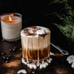 side view of vegan white Russian cocktail with gingerbread spices on dark tray