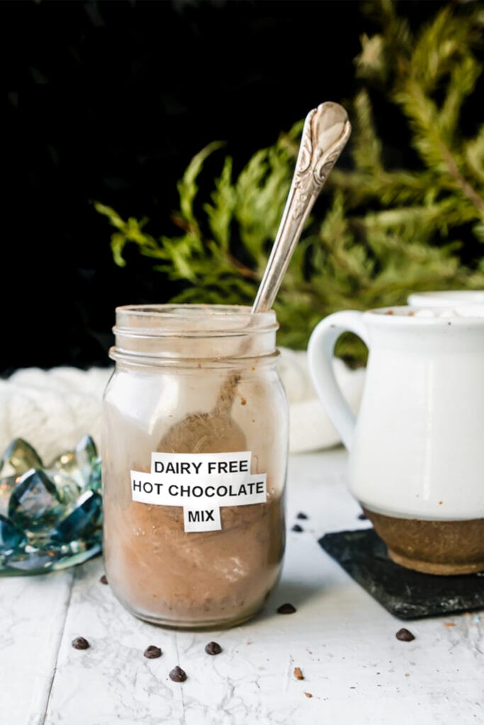 antique spoon dipped into glass mason jar with label "dairy-free hot chocolate mix"