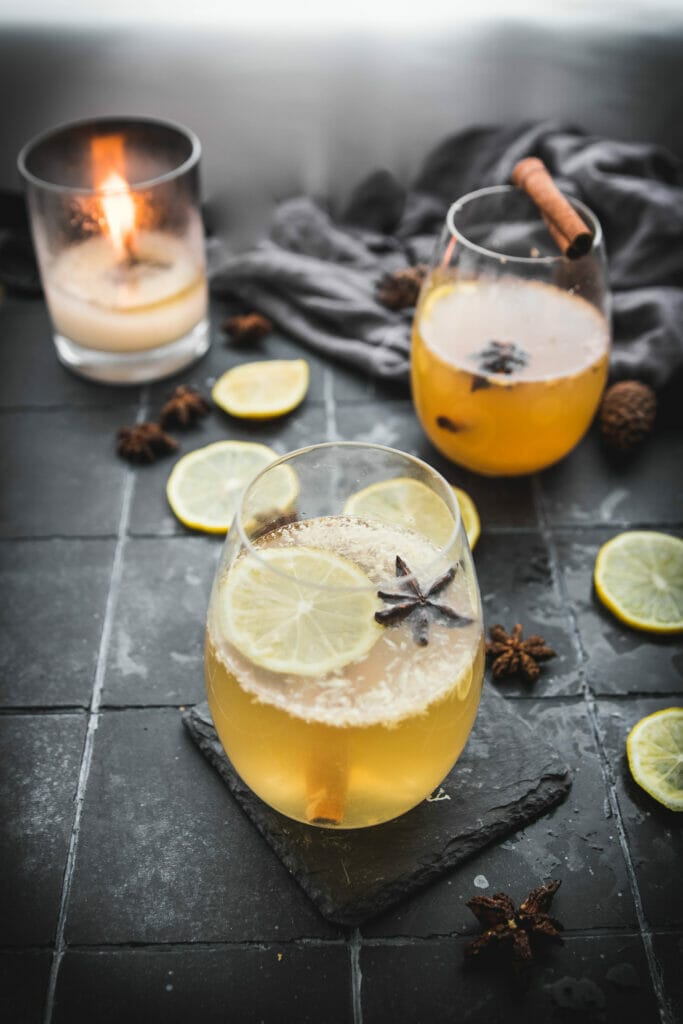 side view of two glasses of hot toddy cocktails next to a candle 