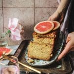 hands placing a grapefruit poppyseed load cake on a tray