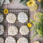 overhead shot of vegan lemon crinkle cookies on a stone table next to yellow flowers