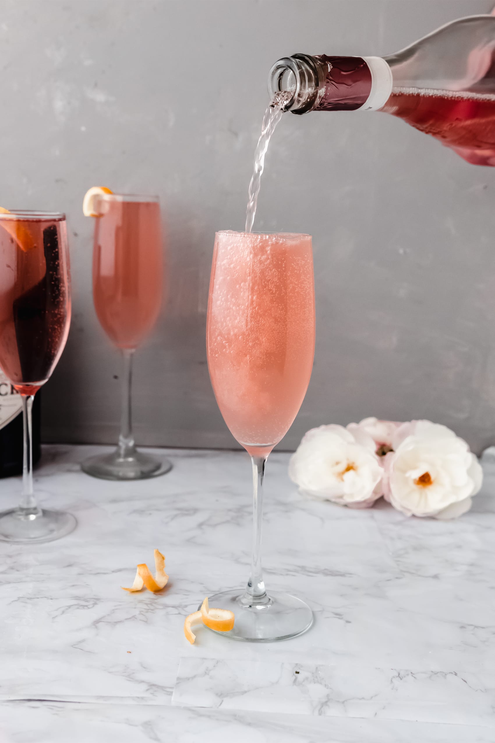 sparkling rose pouring into a champagne flute of rose french 75