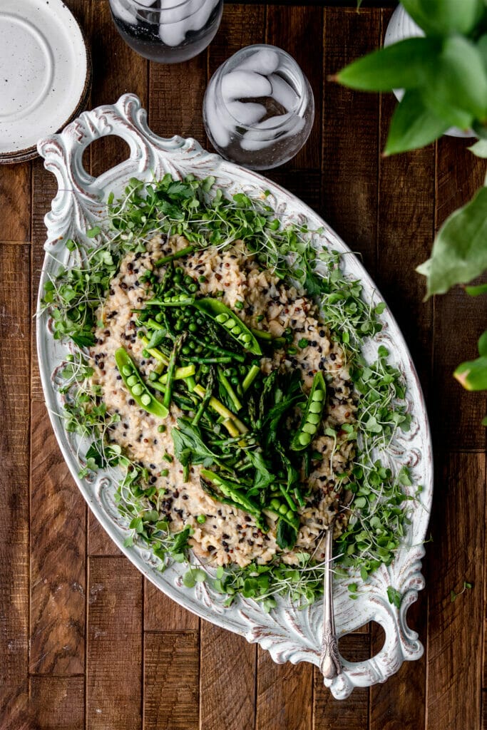 overhead shot of asparagus barley risotto and a wooden table with two glasses of water