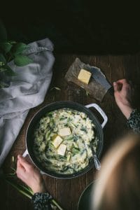 person standing over a white pot with vegan colcannon