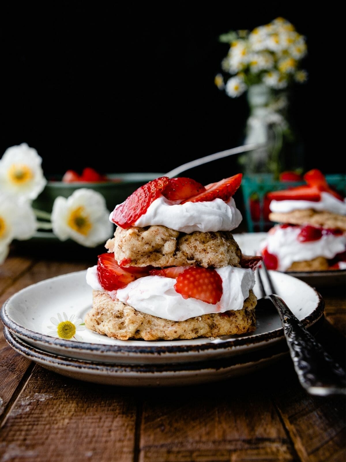 stack of vegan strawberry shortcake with whipped cream on a wooden table
