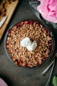 overhead shot of brown butter rhubarb crumble on a stone table with two scoops of vanilla ice cream