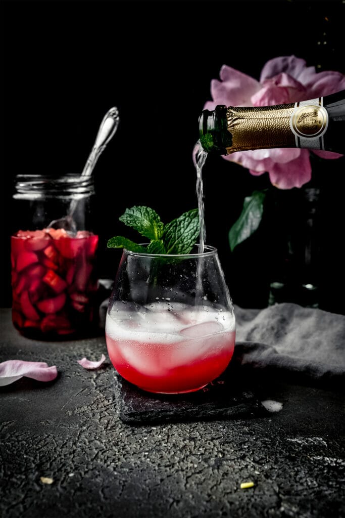 champagne pouring into a glass of rhubarb shrub