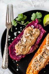 black plate with two instant pot purple sweet potatoes next to a fork