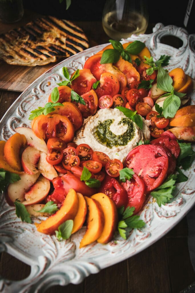 close up of sliced peaches and cherry tomatoes on an appetizer plate