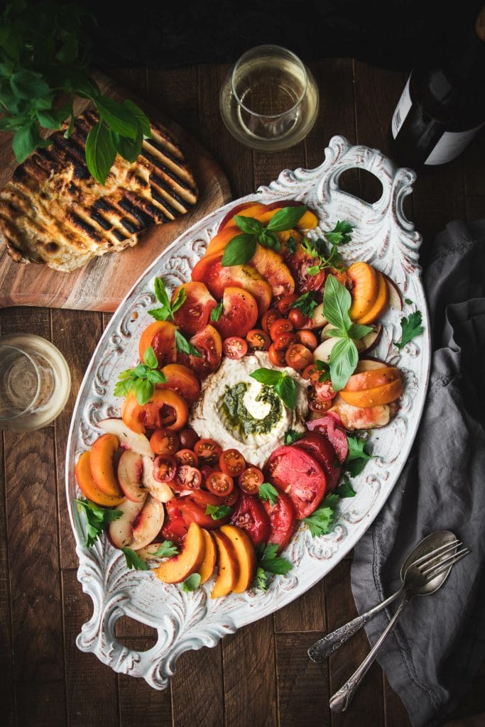 grilled flatbread next to an heirloom tomato and peach summer salad