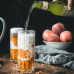 hand pouring a jar of ginger beer into a glass of peach crumble ice cream floats