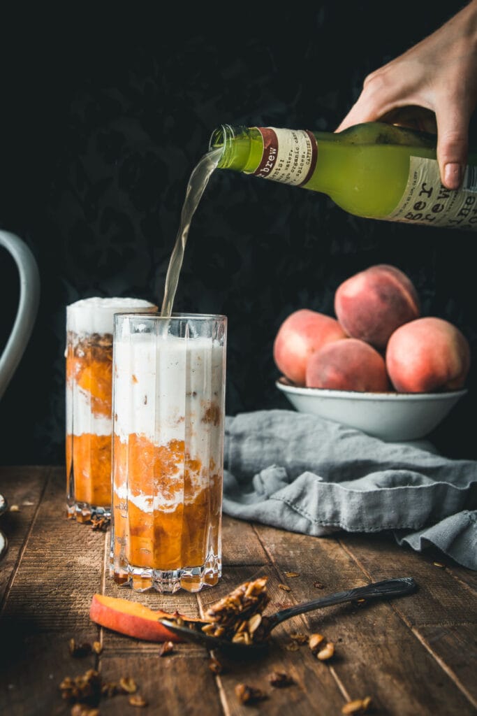 hand pouring a jar of ginger beer into a glass of peach crumble ice cream floats