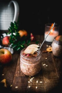 side view of apple pie overnight oats on a wooden table next to an apple