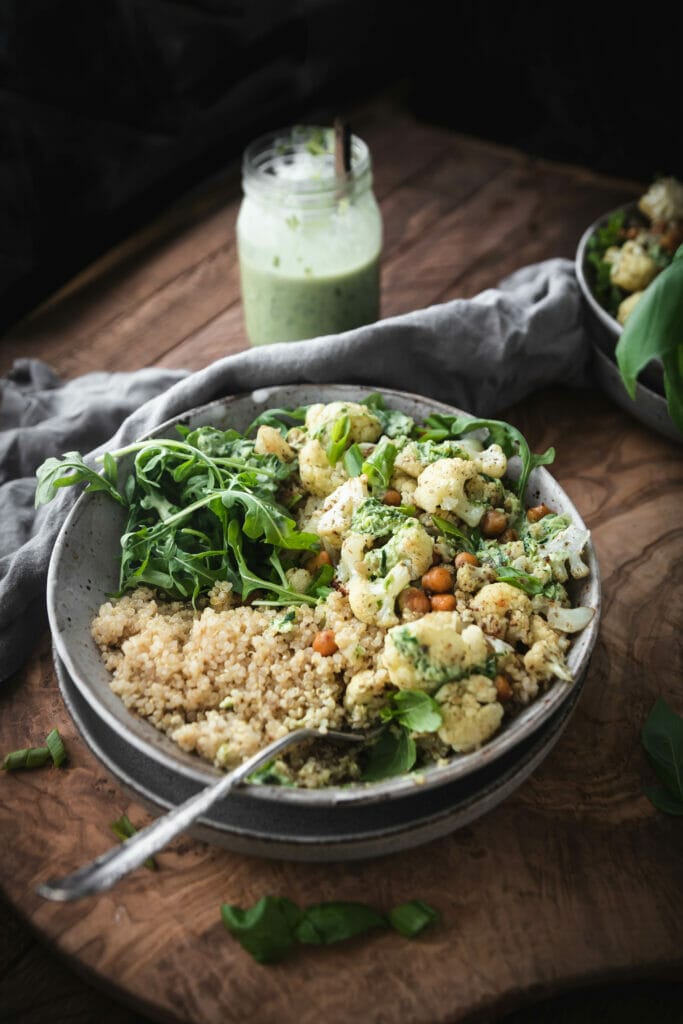 side view of ovehead shot of cauliflower quinoa bowl on a wooden table