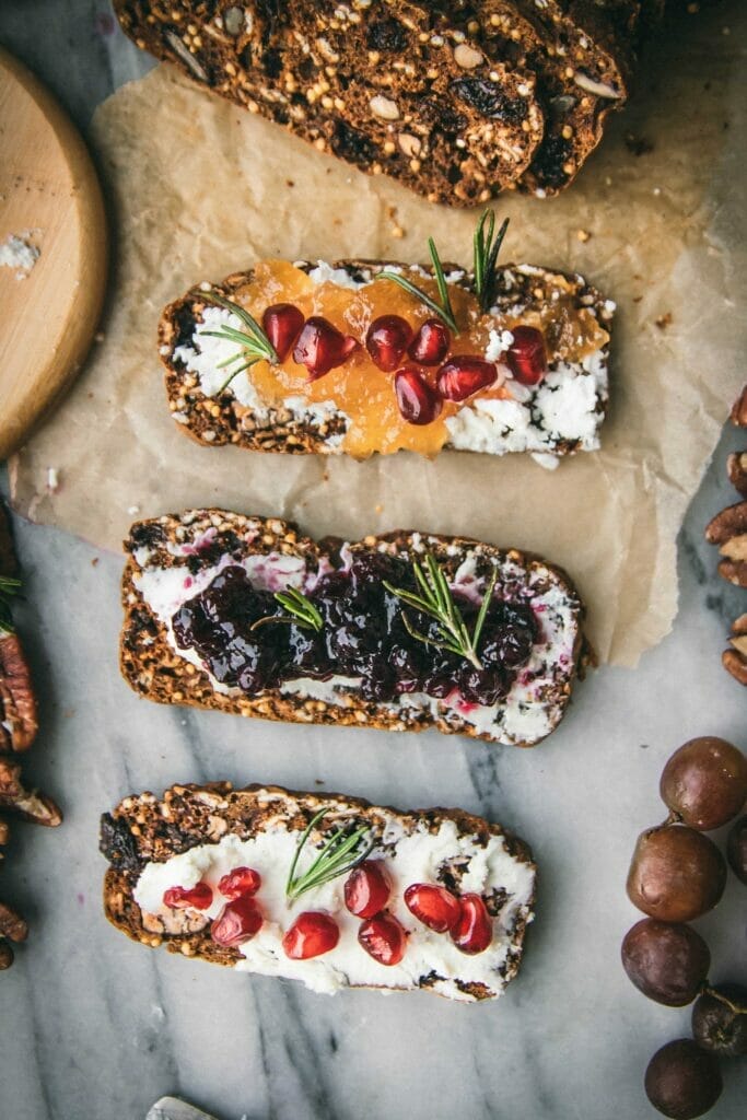 line of three gourmet crackers on a marble cheese plate with various toppings